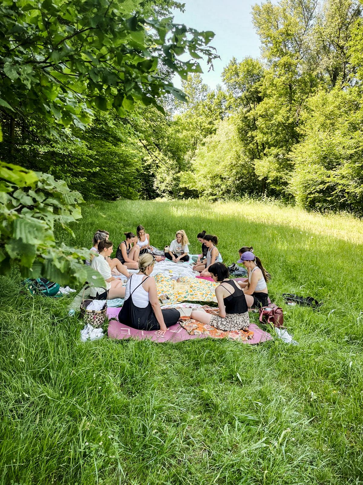 Eine Gruppe von Frauen sitzt in der Wiese und arbeitet mit Ton